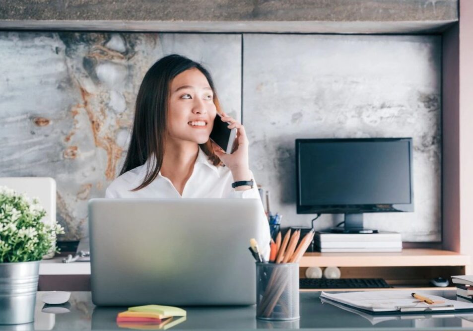 A woman sitting at her desk talking on the phone.