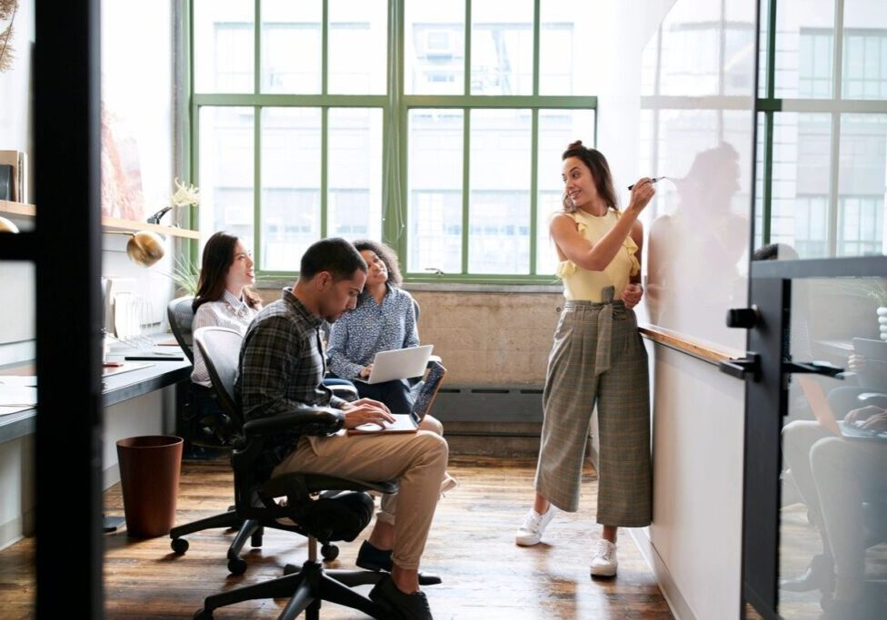 A group of people sitting in front of a whiteboard.