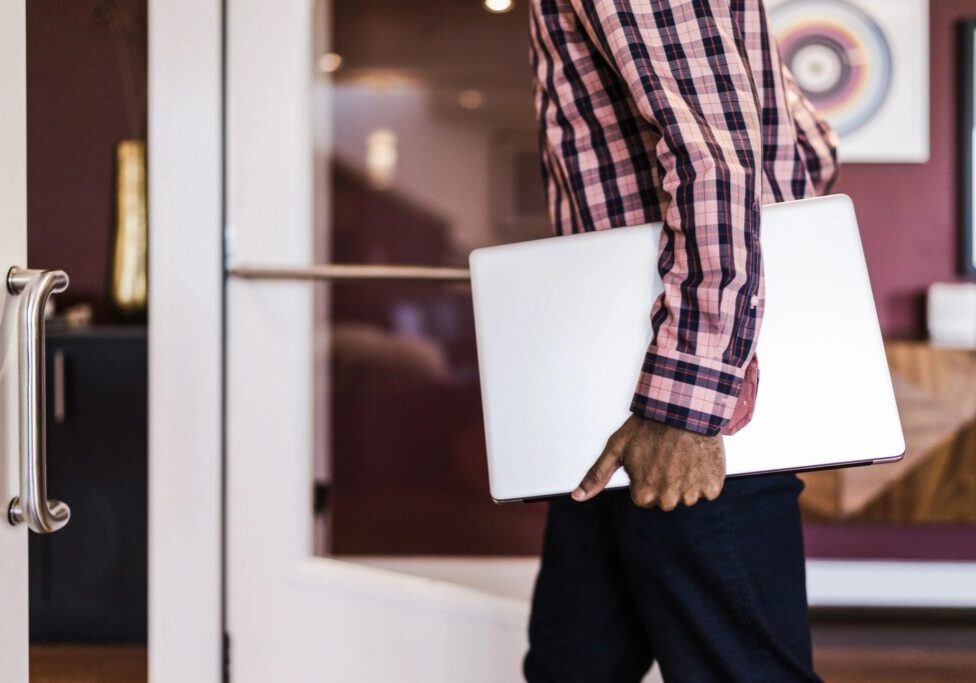 A man holding a laptop in his hand.