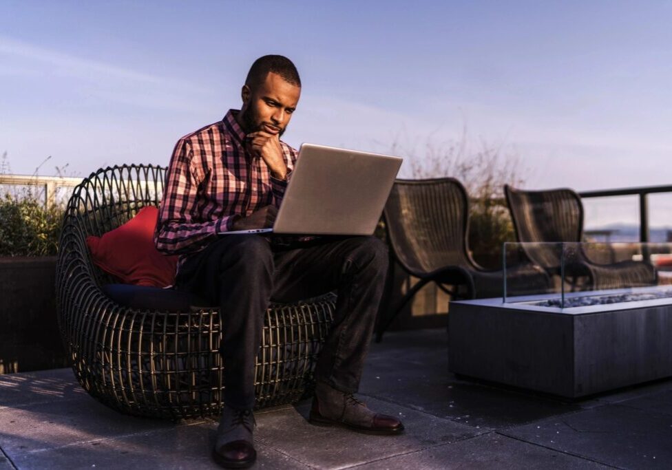 A man sitting on top of a chair using his laptop.