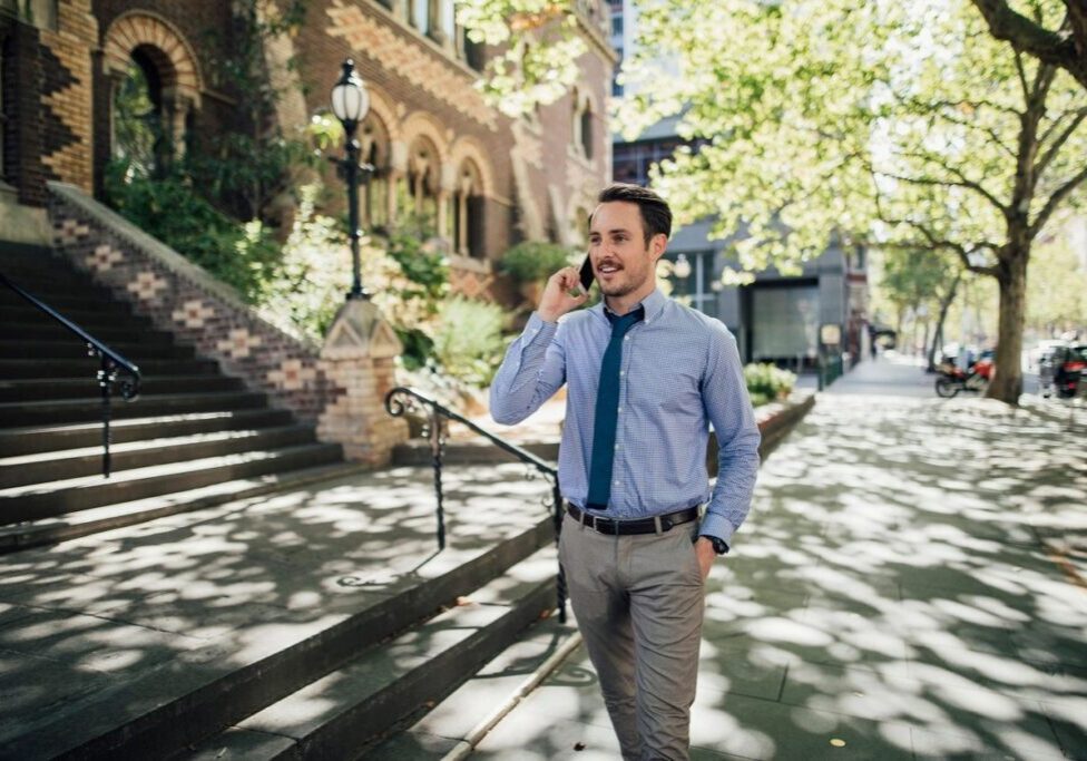 A man in blue shirt and tie talking on phone.