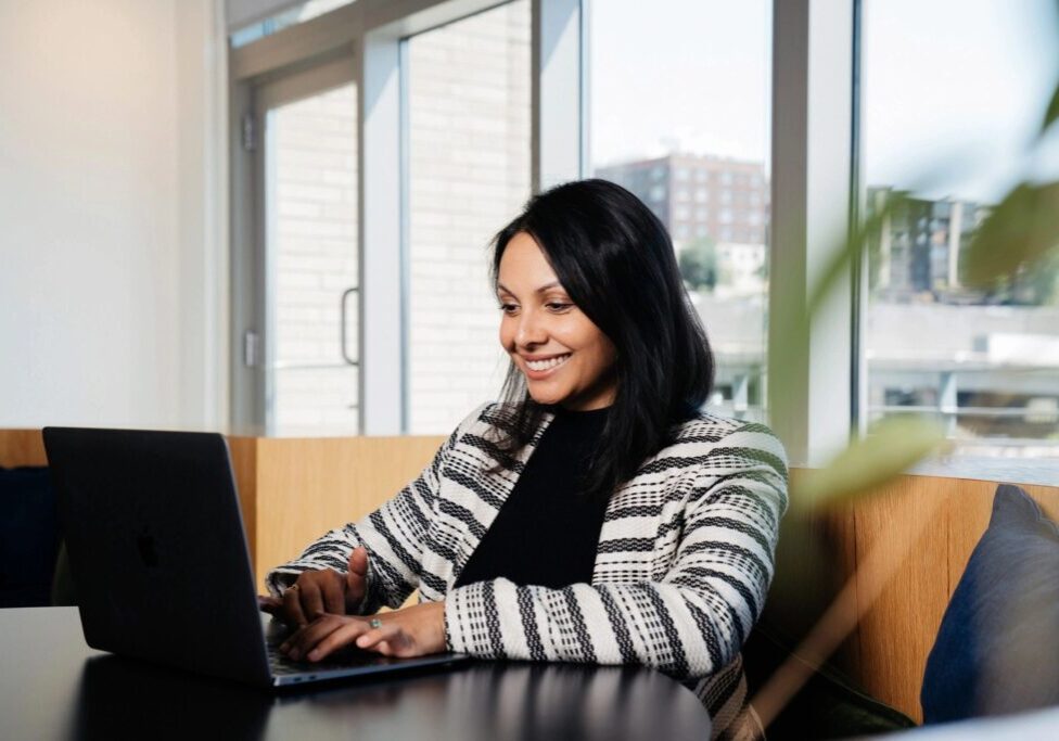 A woman sitting at a table with her laptop.