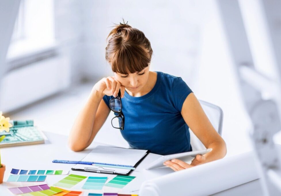 A woman sitting at a table looking down at papers.